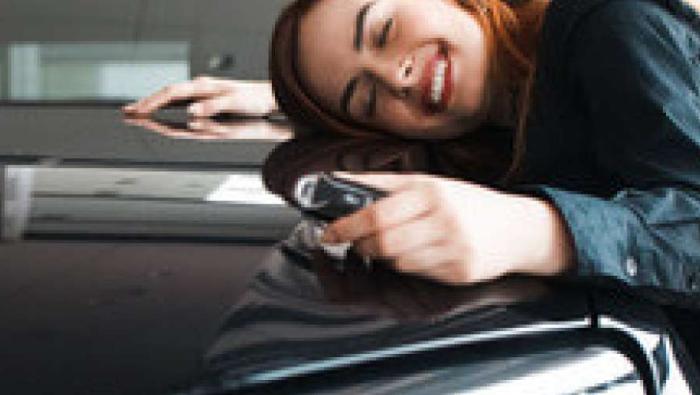 Une femme fait un câlin à sa voiture d'occasion car elle a trouvé son financement